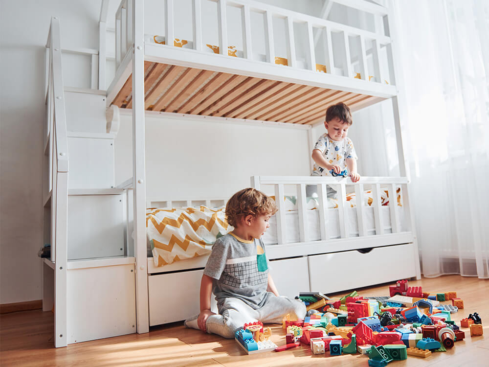 deux enfants jouant devant un lit superposé